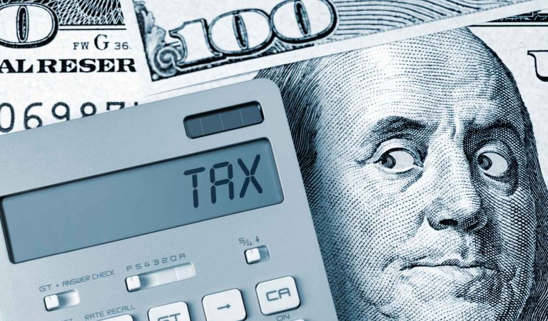 Tax. Benjamin Franklin looking calculator on One Hundred Dollar Bill.